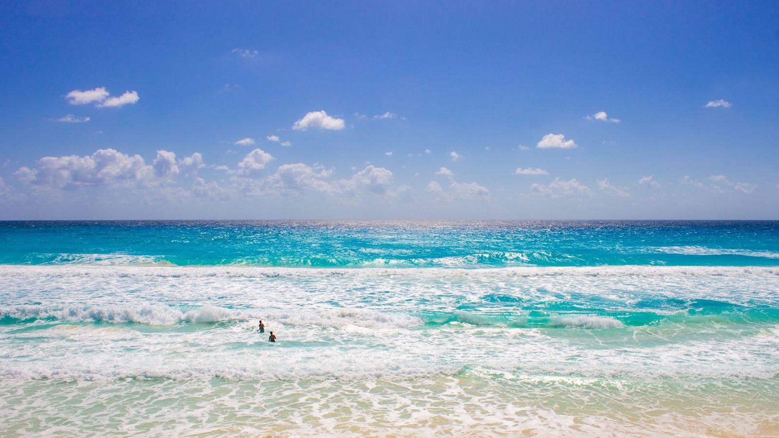 Vibrant beach scene in Cancún with clear blue water and sunny skies.